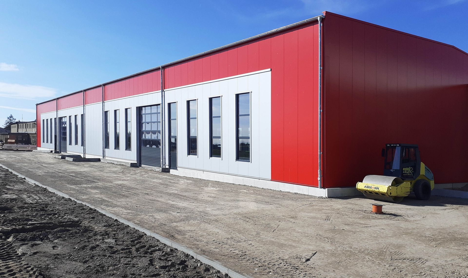 A large red and white building with a yellow forklift parked in front of it.