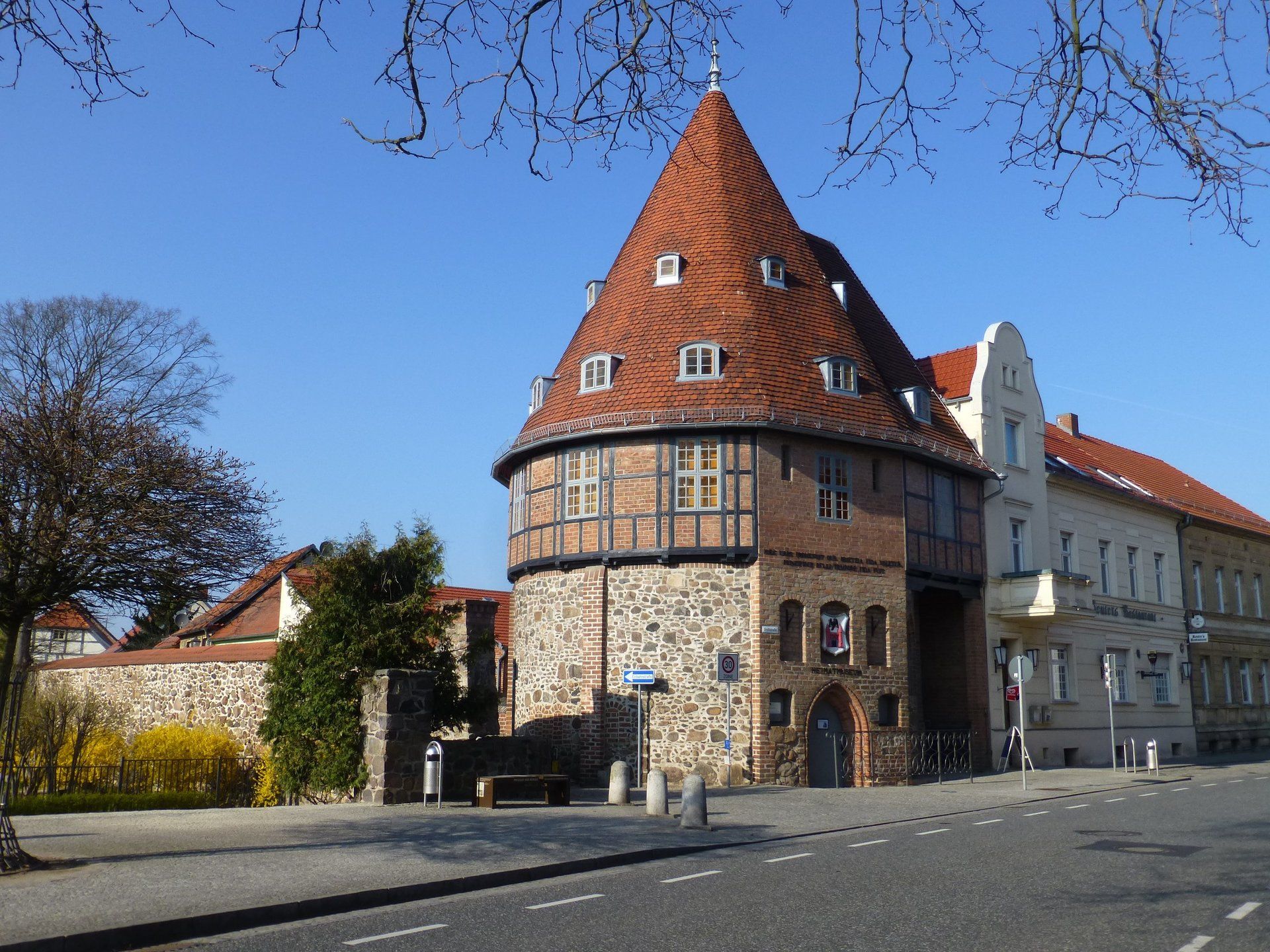A brick building with a red roof and a round tower