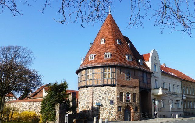 A brick building with a red roof is surrounded by trees.