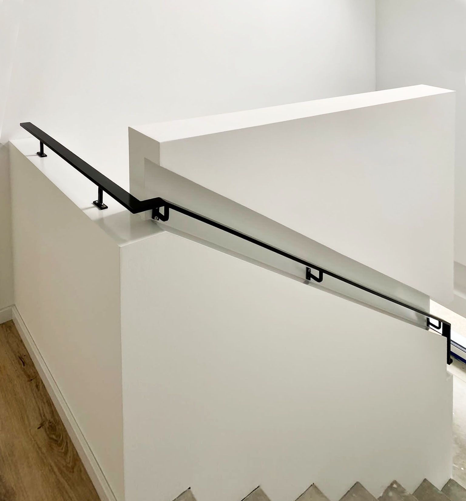 A staircase with a black railing and a white wall
