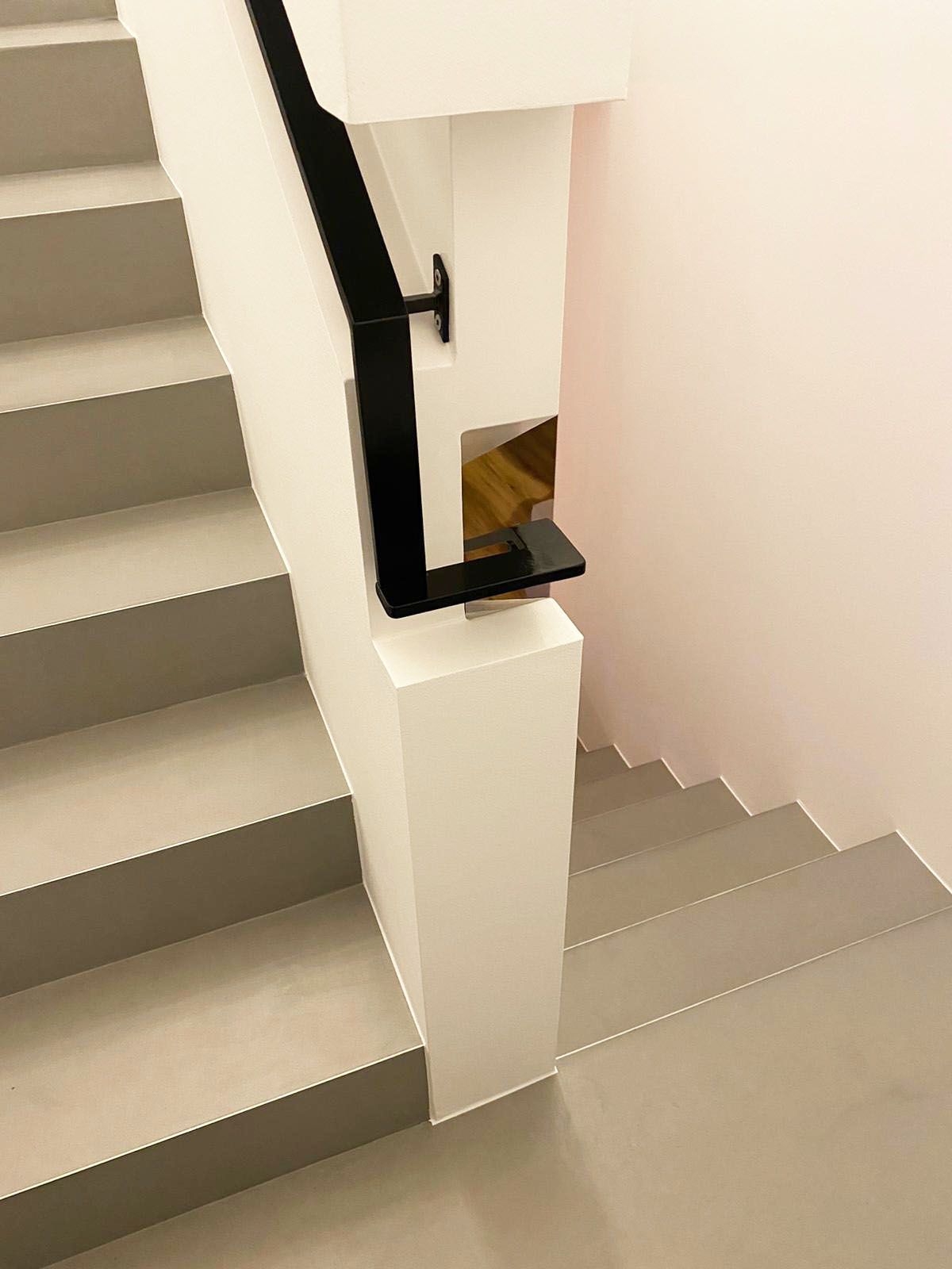 A staircase with a black railing and a white wall.