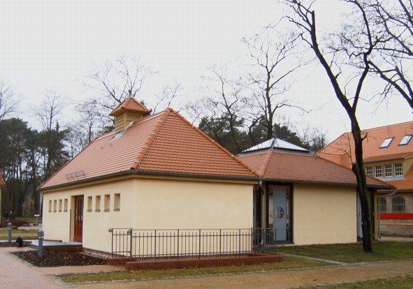 A small white building with a red tiled roof