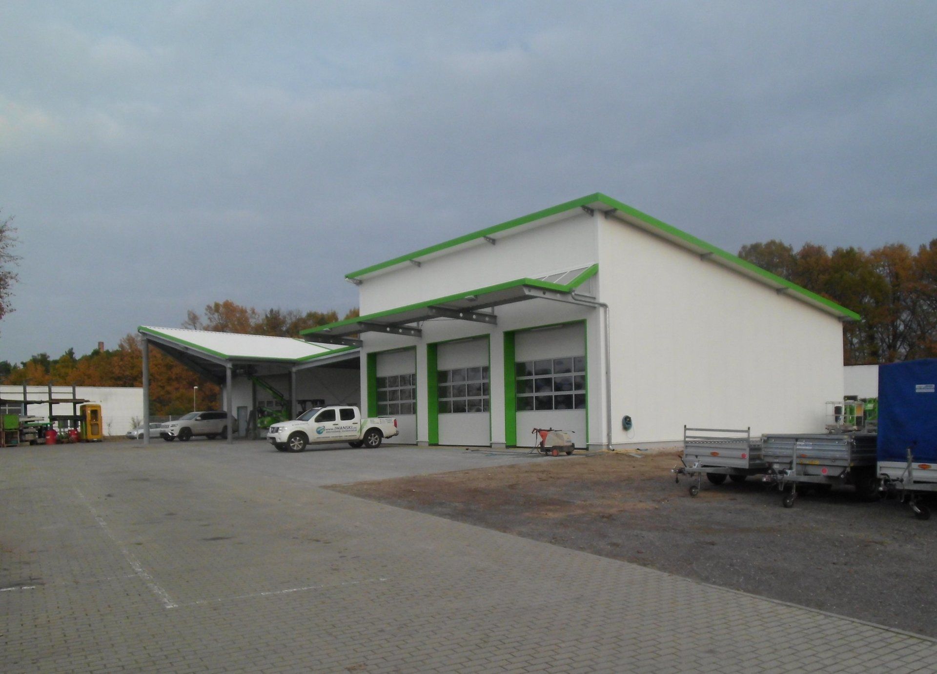 A white truck is parked in front of a building with green trim.