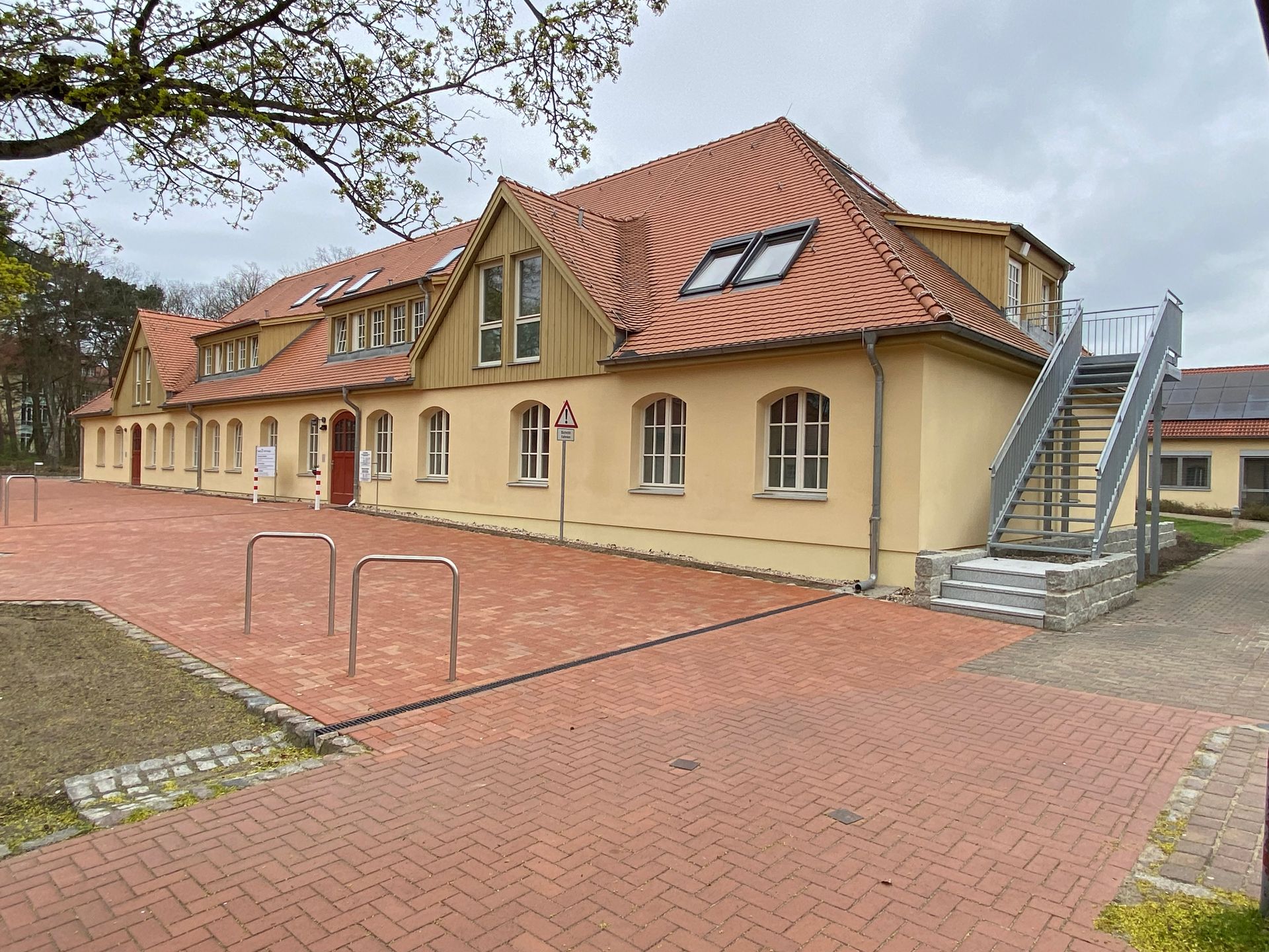 Ein großes gelbes Gebäude mit einem roten Ziegeldach und Treppen