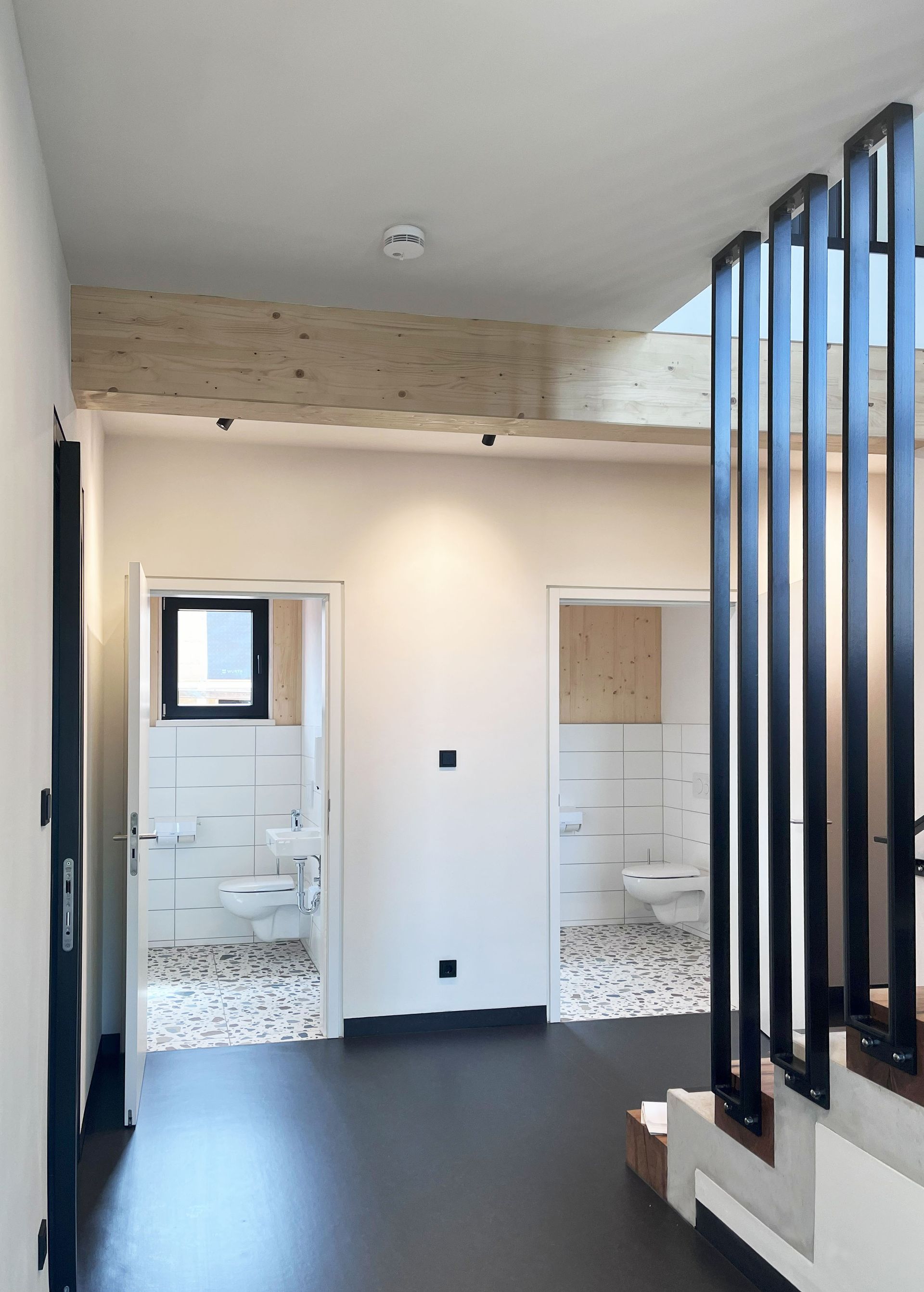 Ein Flur mit Treppe, die zu einem Badezimmer und einer Toilette führt.