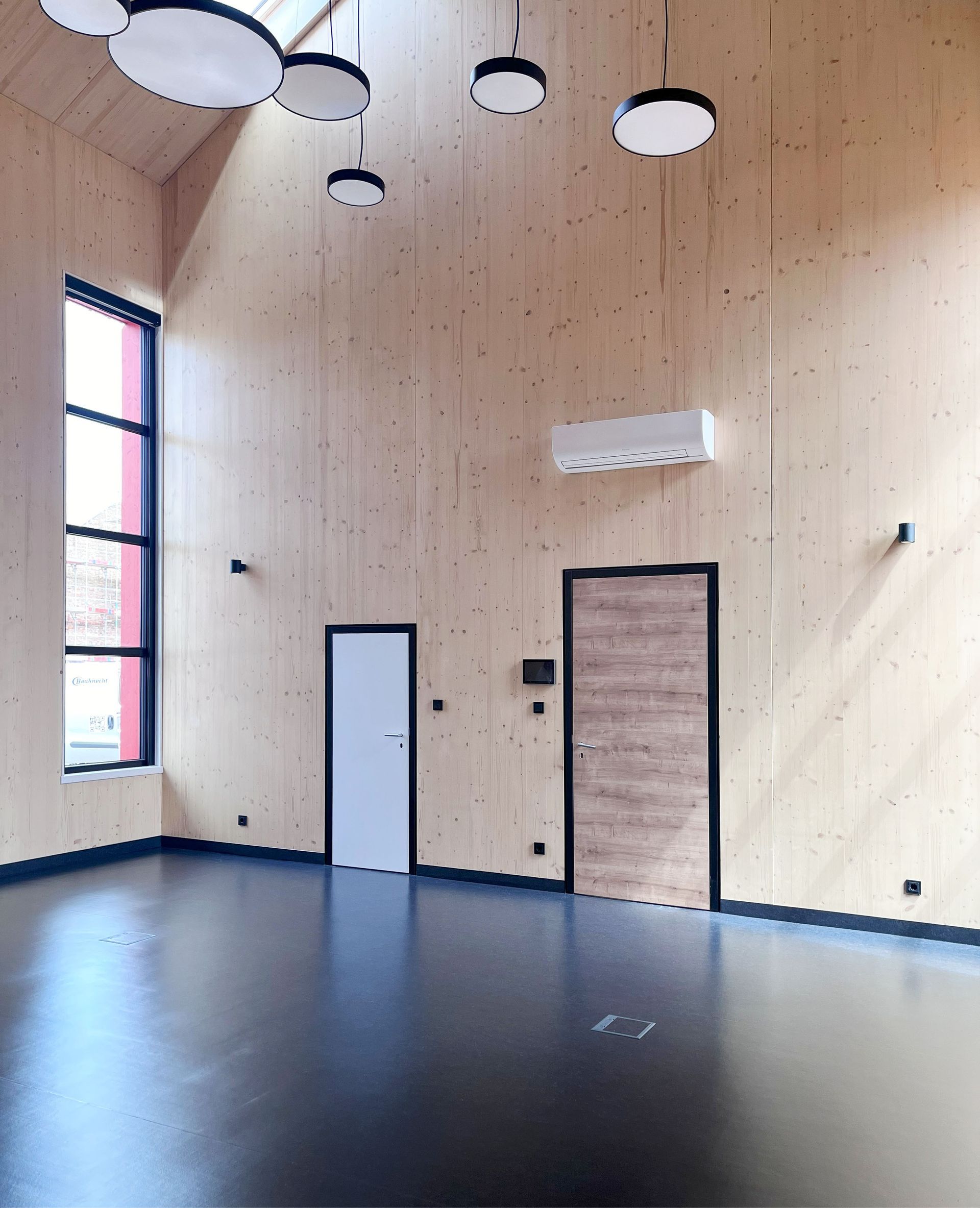 Ein leerer Raum mit Holzwänden und schwarzem Boden