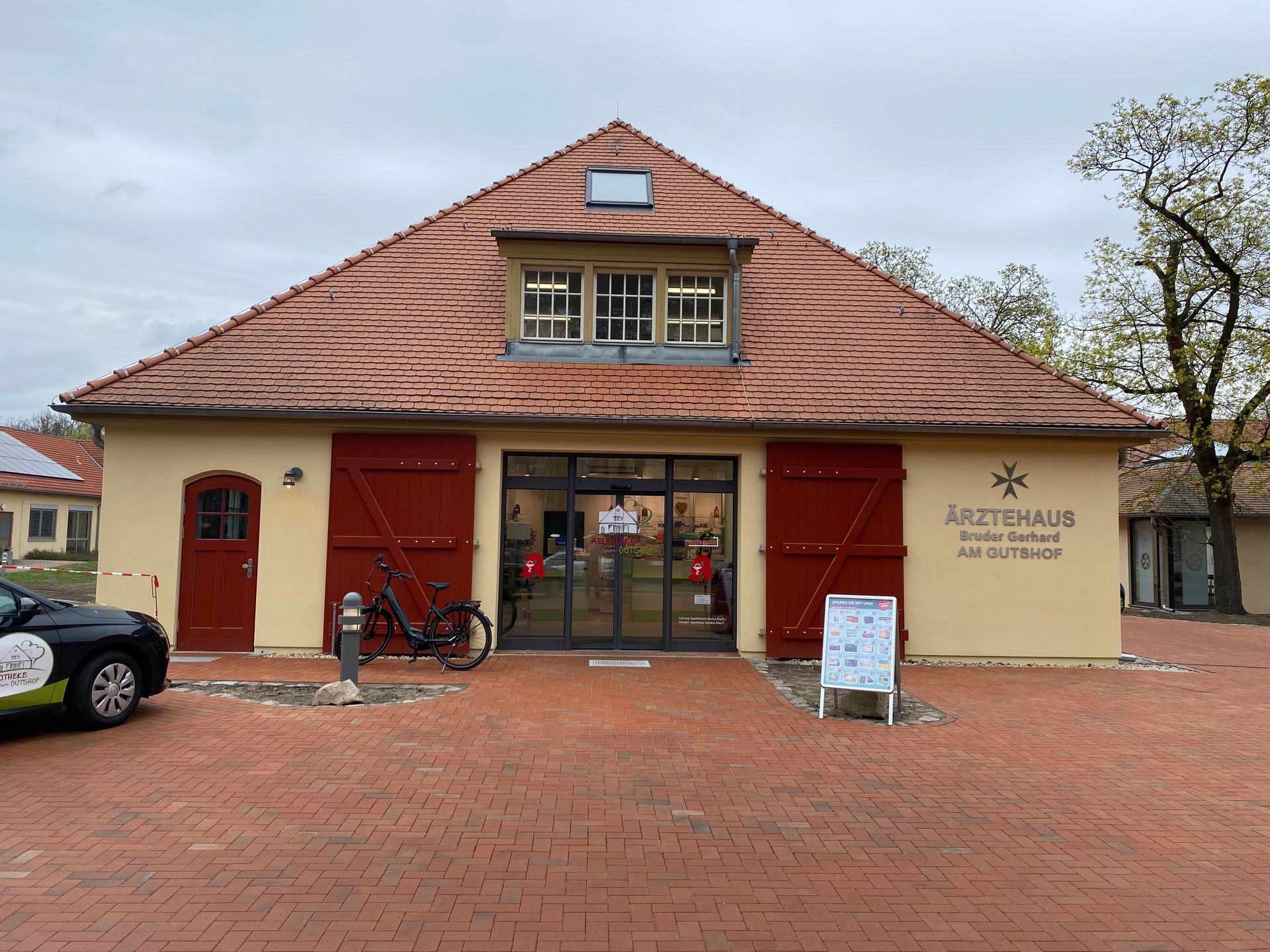 Ein gelbes Gebäude mit roten Türen und einem davor geparkten Fahrrad.