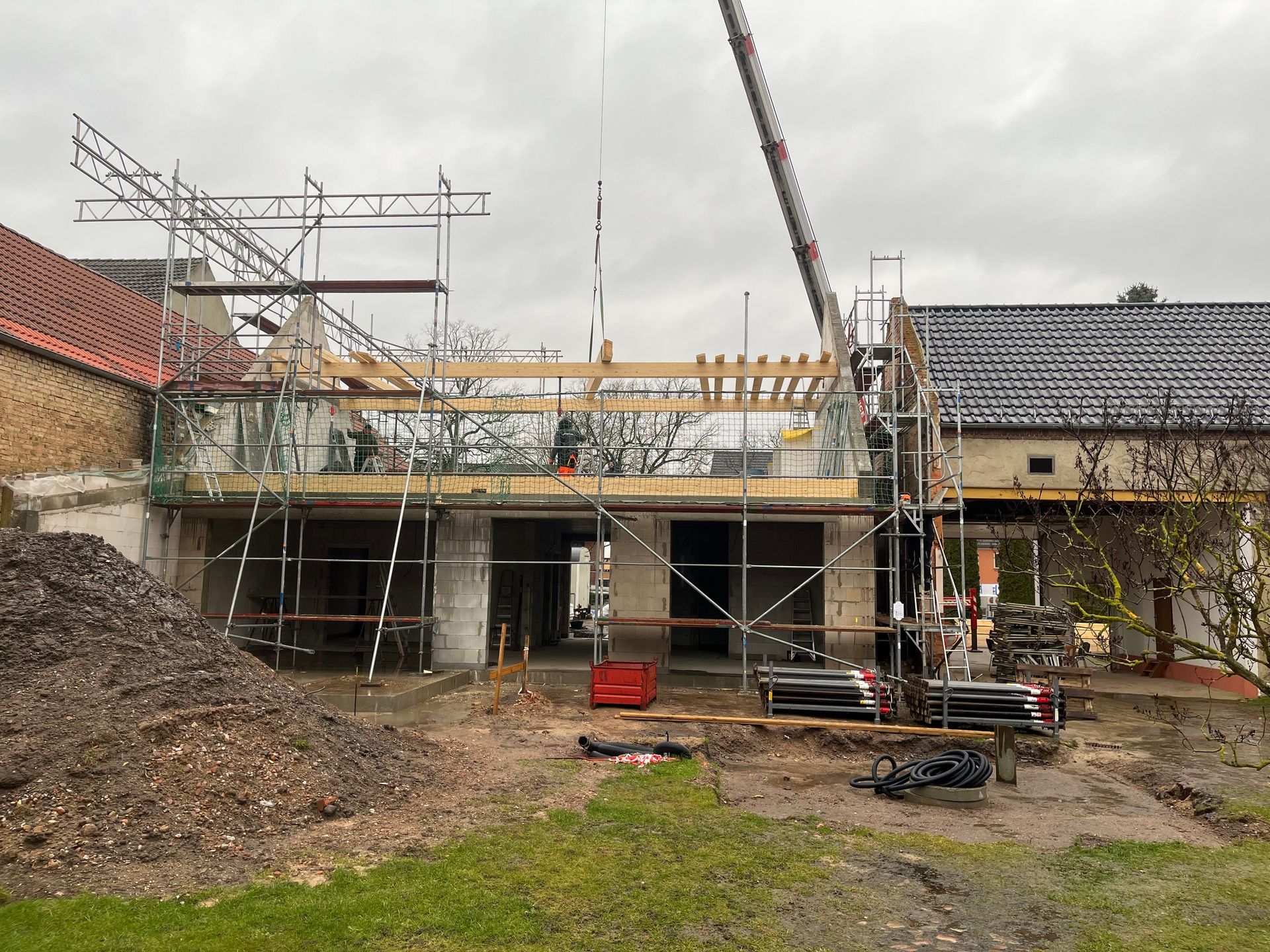 Mit Gerüst und Kran wird ein Haus gebaut.