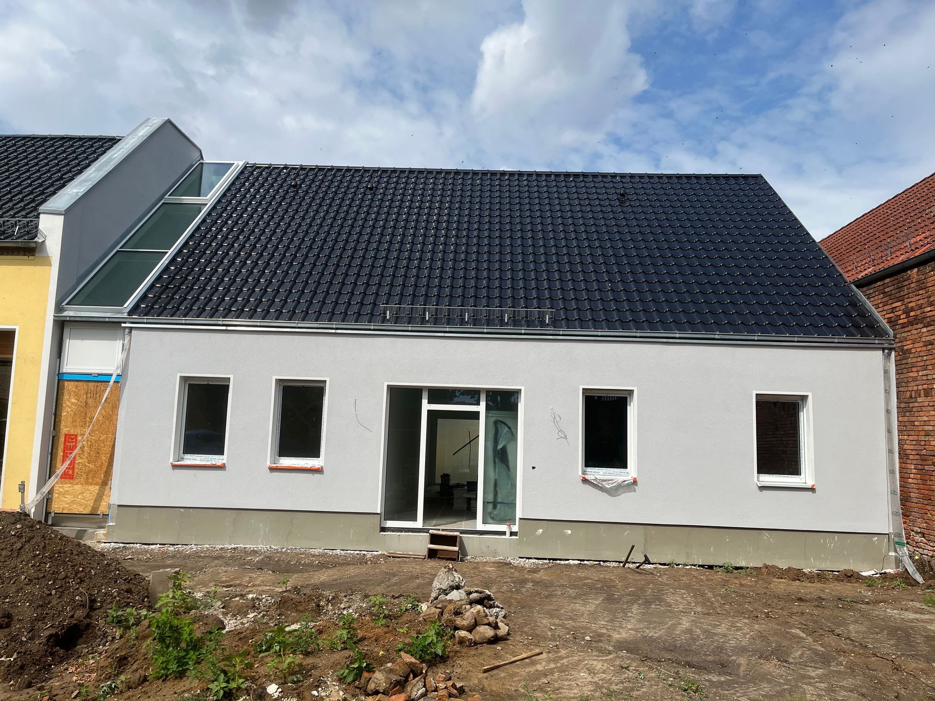 Vor einem Backsteingebäude liegt ein Holzpfosten im Dreck.