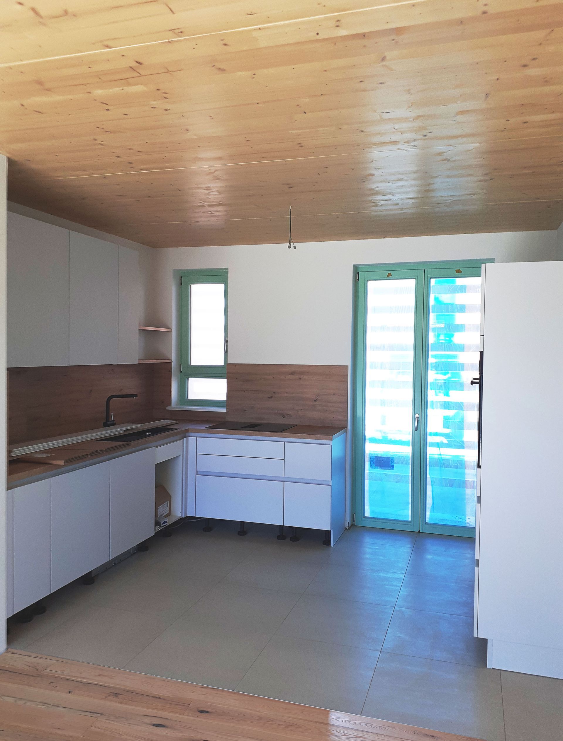 Eine Küche mit weißen Schränken und einer Holzdecke