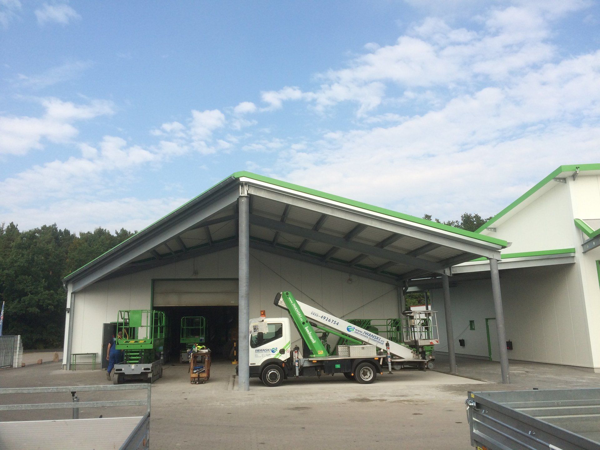 A green truck is parked in front of a building with a green roof.