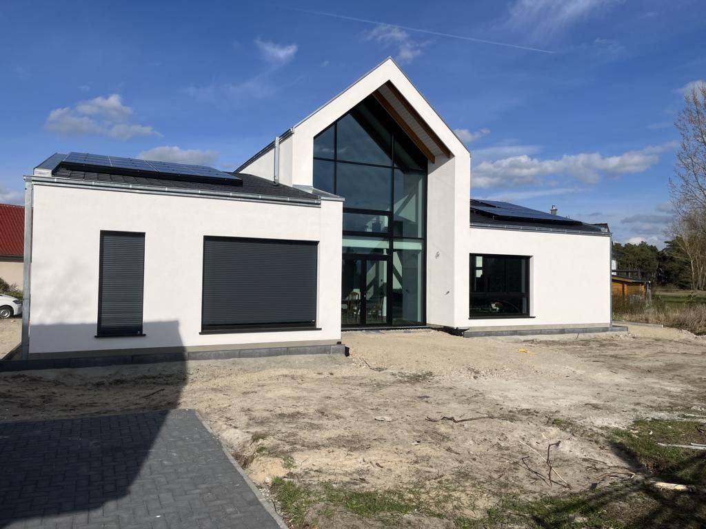 A white house with a lot of windows and solar panels on the roof.