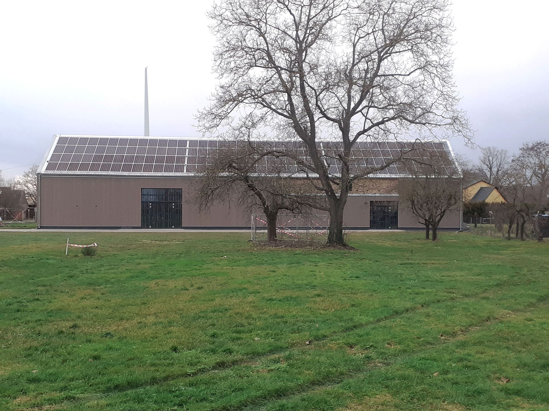 Inmitten einer Wiese steht ein großes Gebäude mit Solarzellen auf dem Dach.