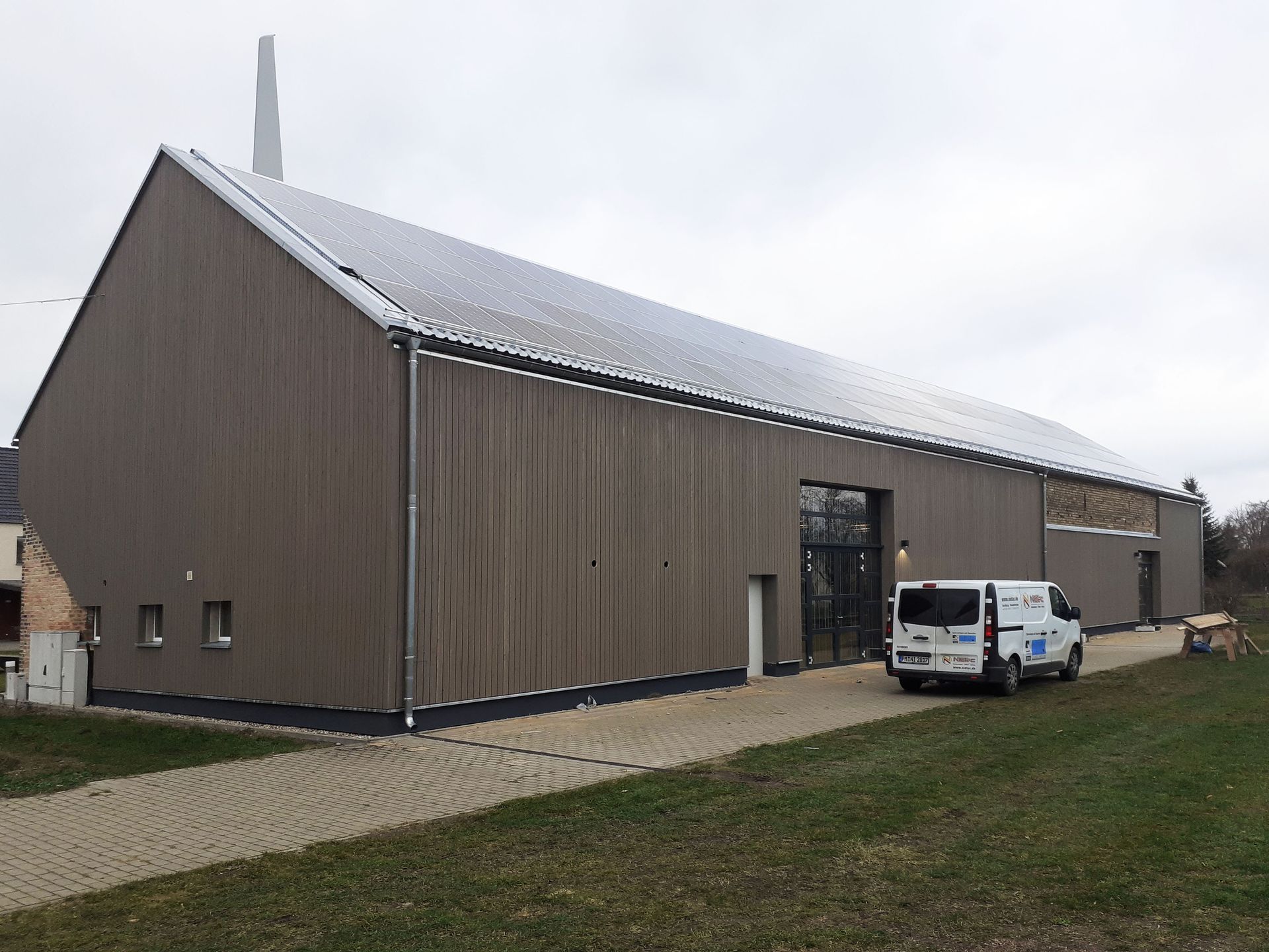 Ein weißer Lieferwagen parkt vor einem großen Gebäude.