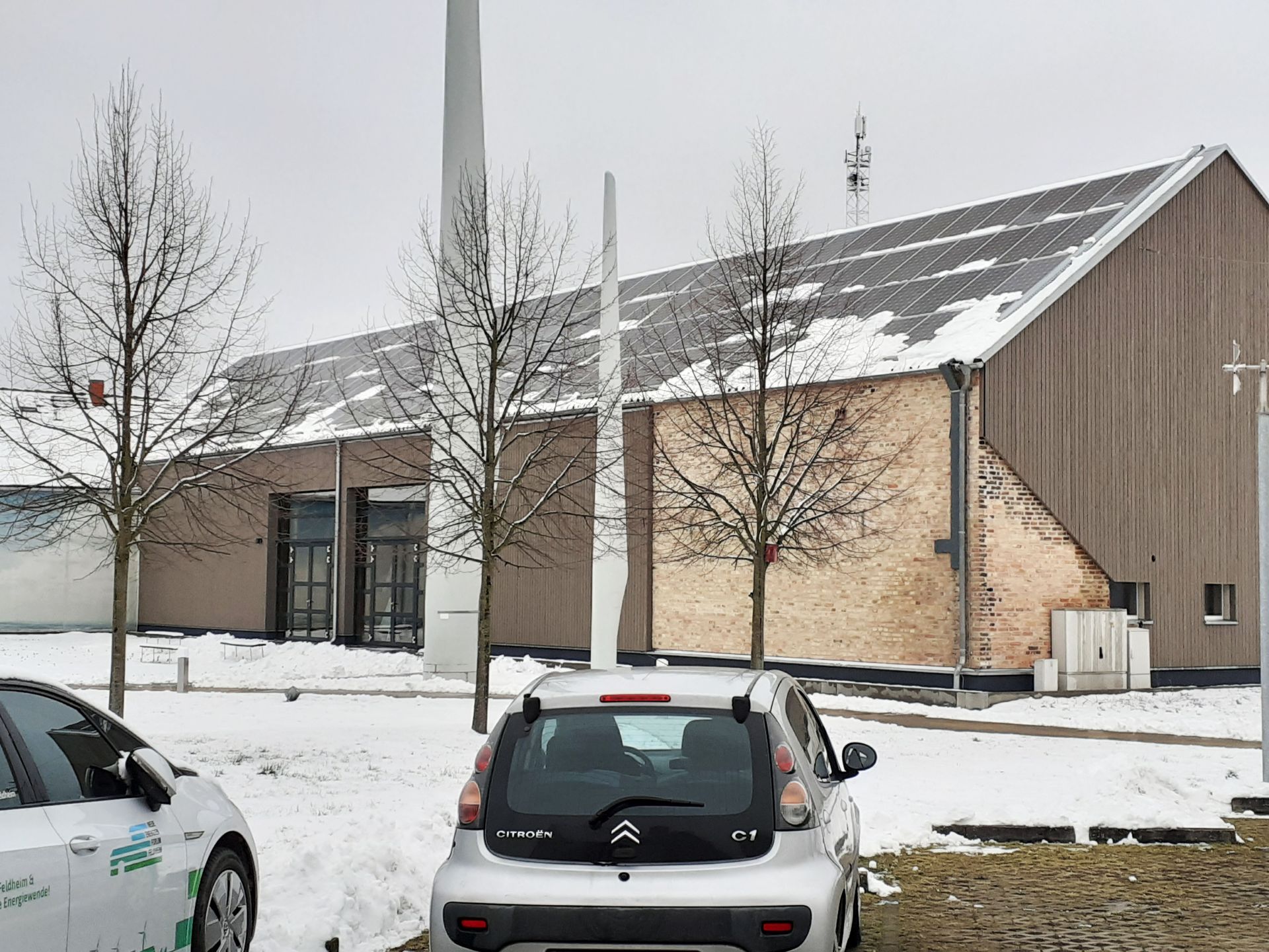 Zwei Autos sind im Schnee vor einem Gebäude geparkt.