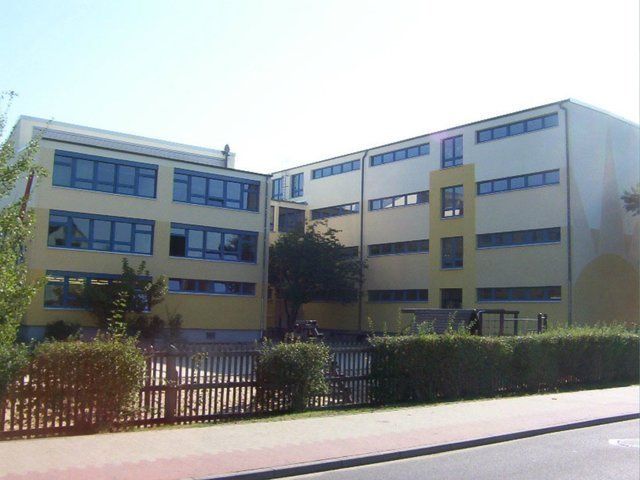 A large yellow and white building with a fence in front of it