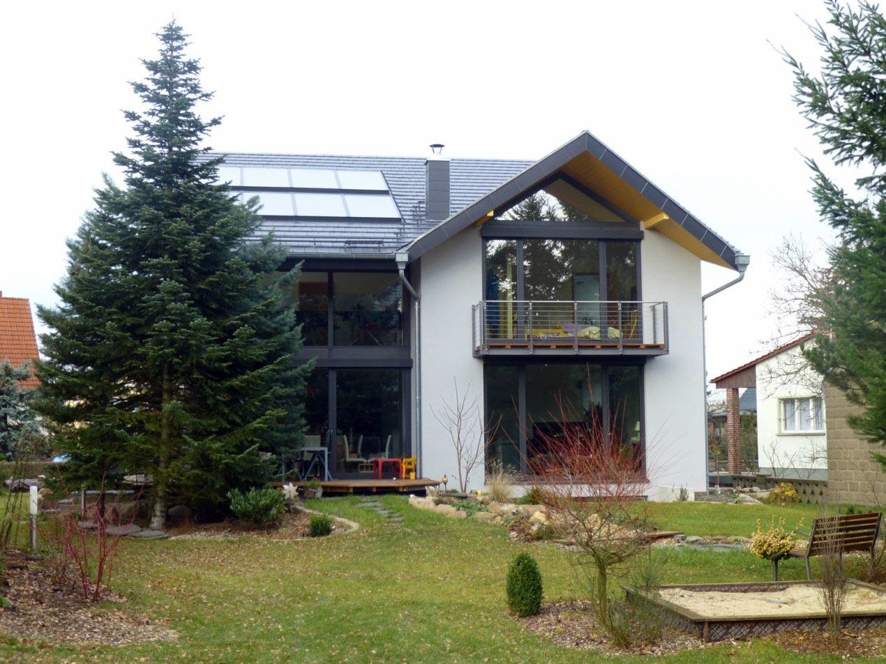 A large white house with a balcony and solar panels on the roof