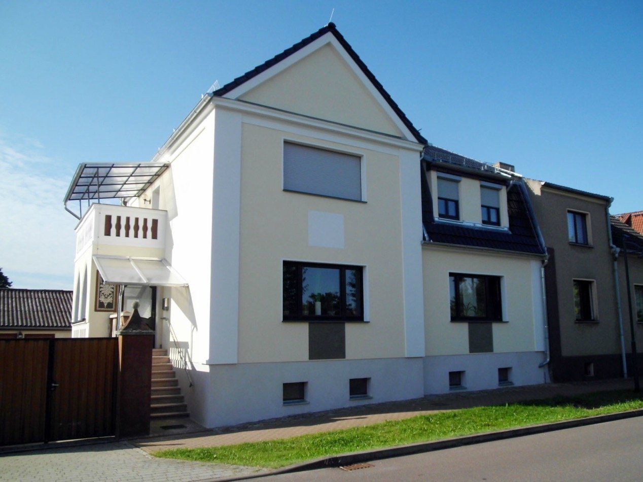 A large white house with black windows and a balcony