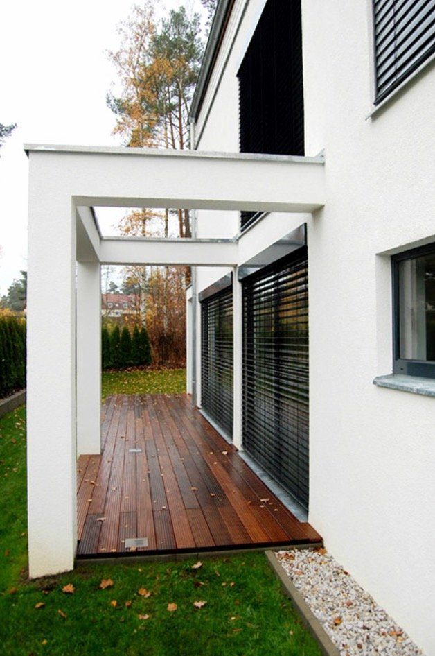 A white house with a wooden deck and black blinds