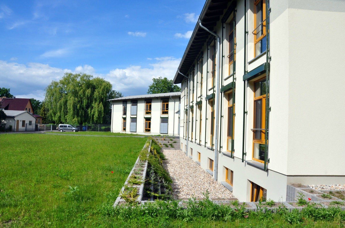 A large white building with a lot of windows is sitting in the middle of a grassy field.