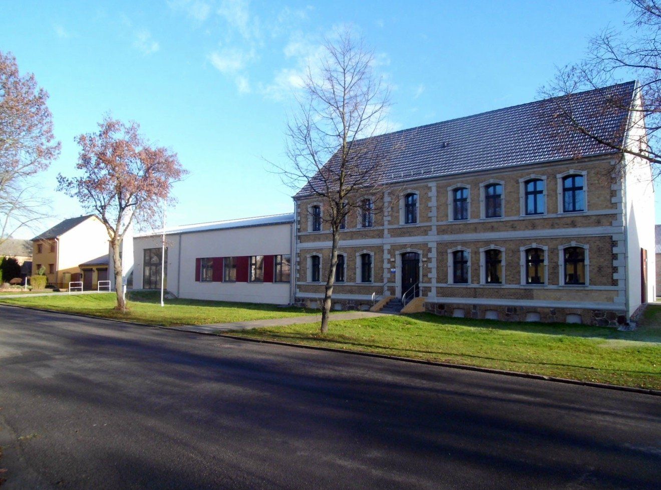 A large building with a lot of windows is next to a smaller building.