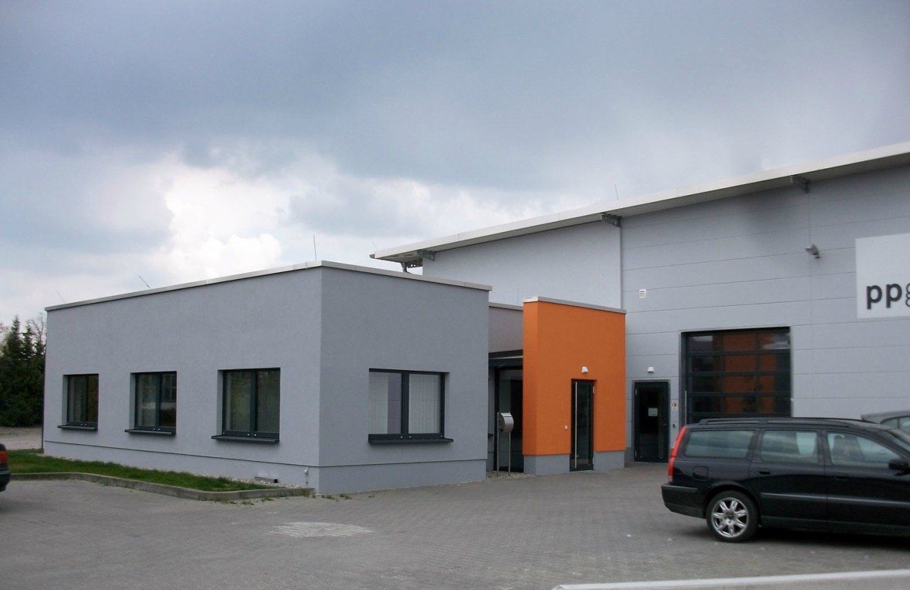 A car is parked in front of a building that says pp