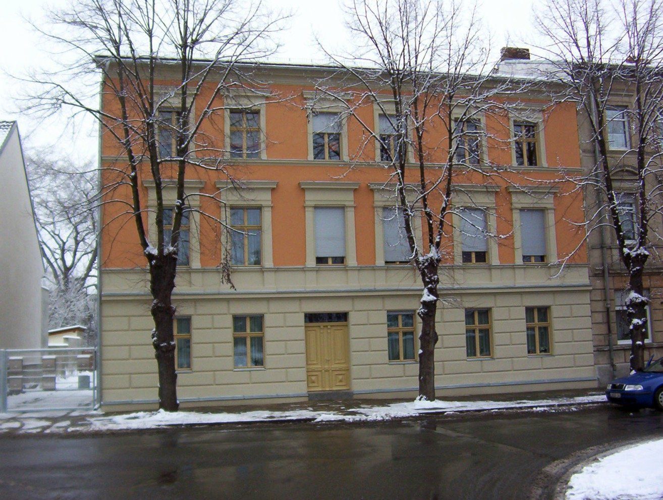 A building with a yellow door and trees in front of it