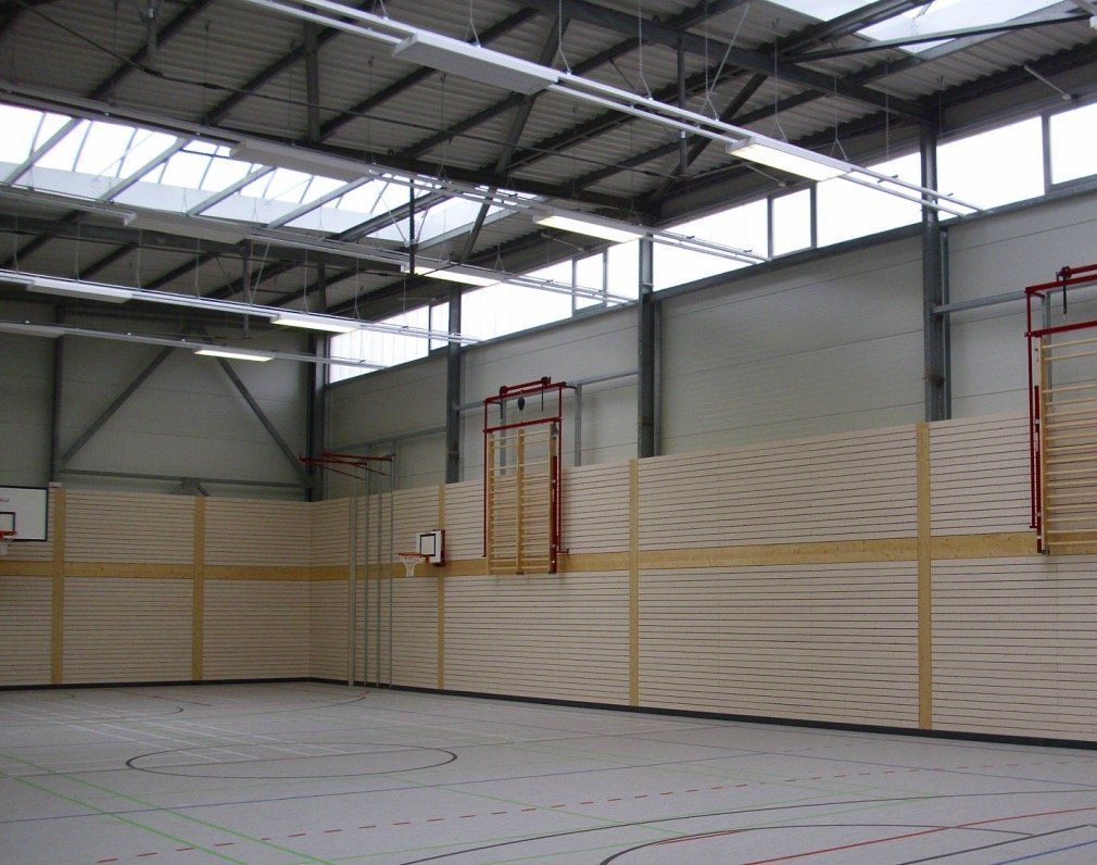 An empty gym with a basketball hoop in the middle