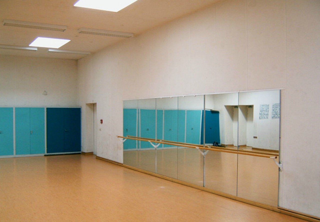 An empty dance studio with a large mirror on the wall