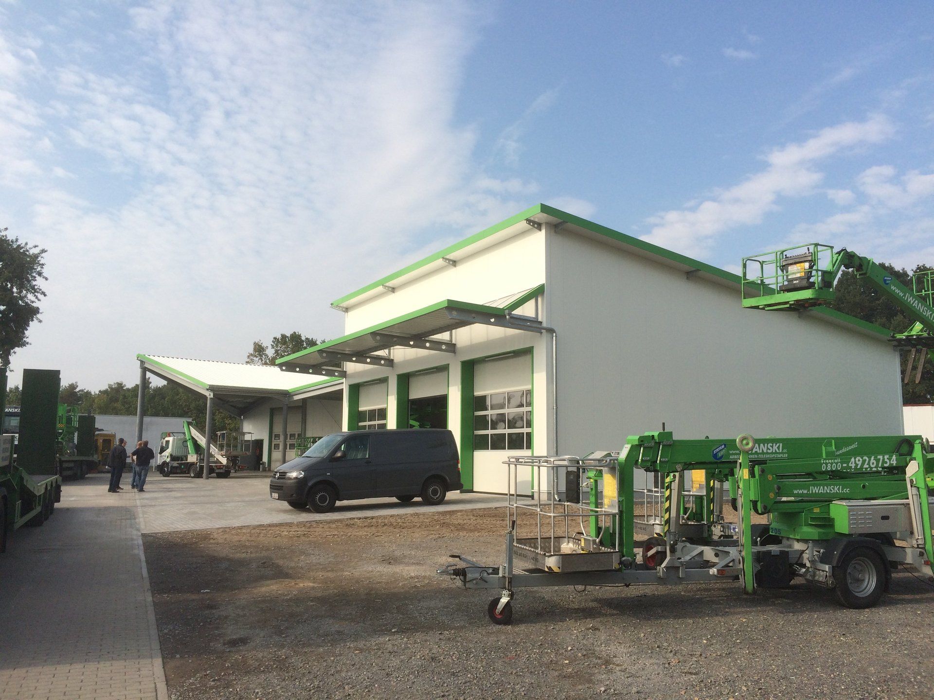 A green aerial lift is parked in front of a building