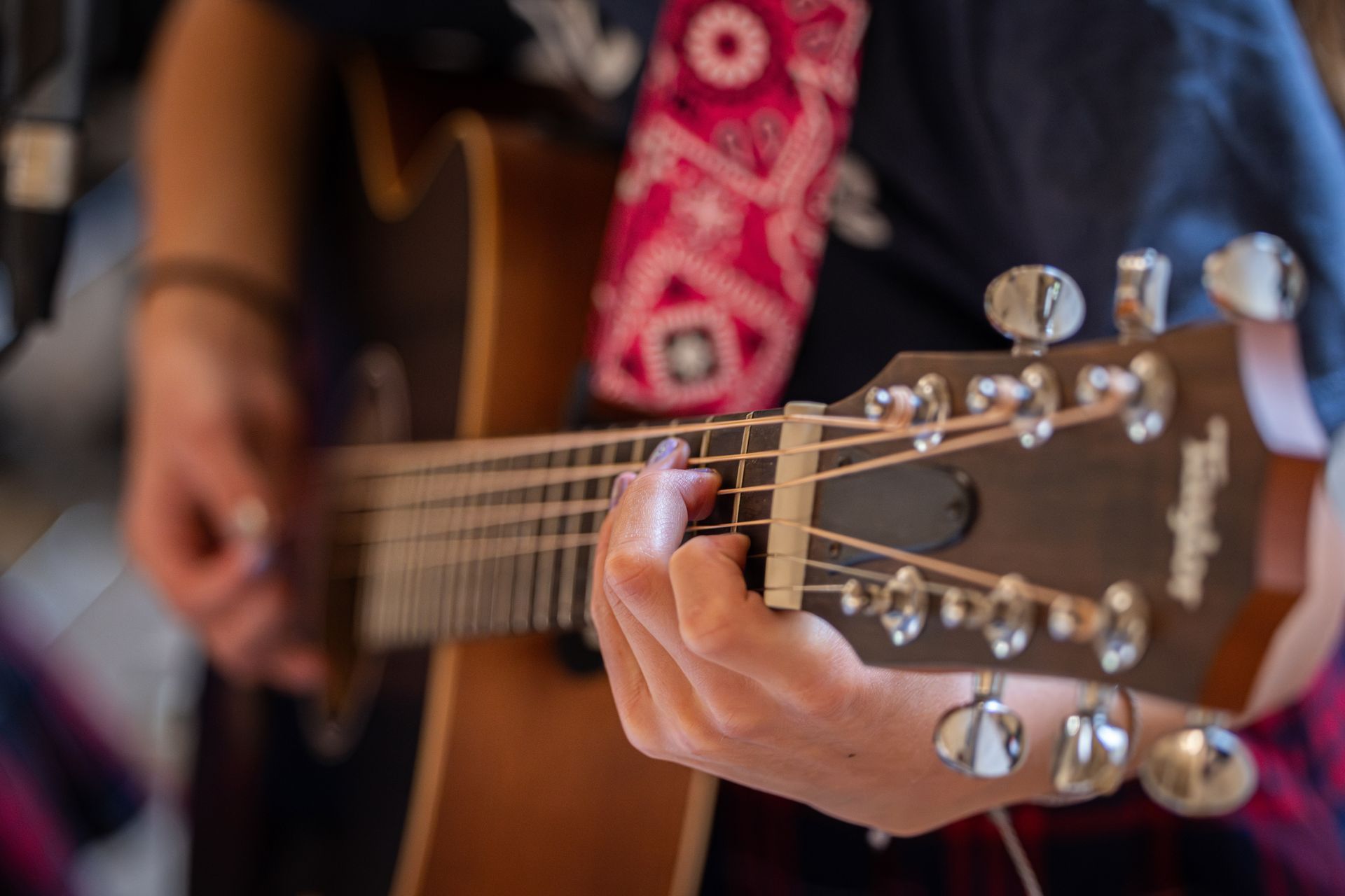 Hands strumming a brown acoustic guitar. Close-up, strings in focus.