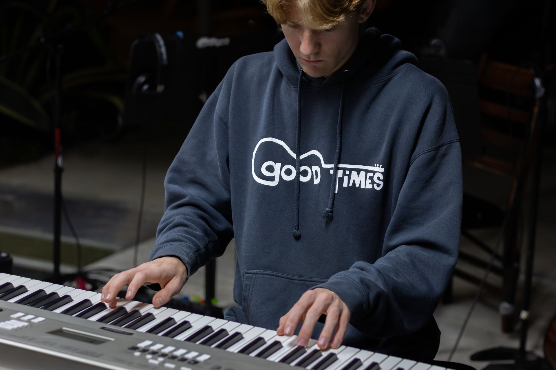 Person playing keyboard, wearing a blue hoodie with 
