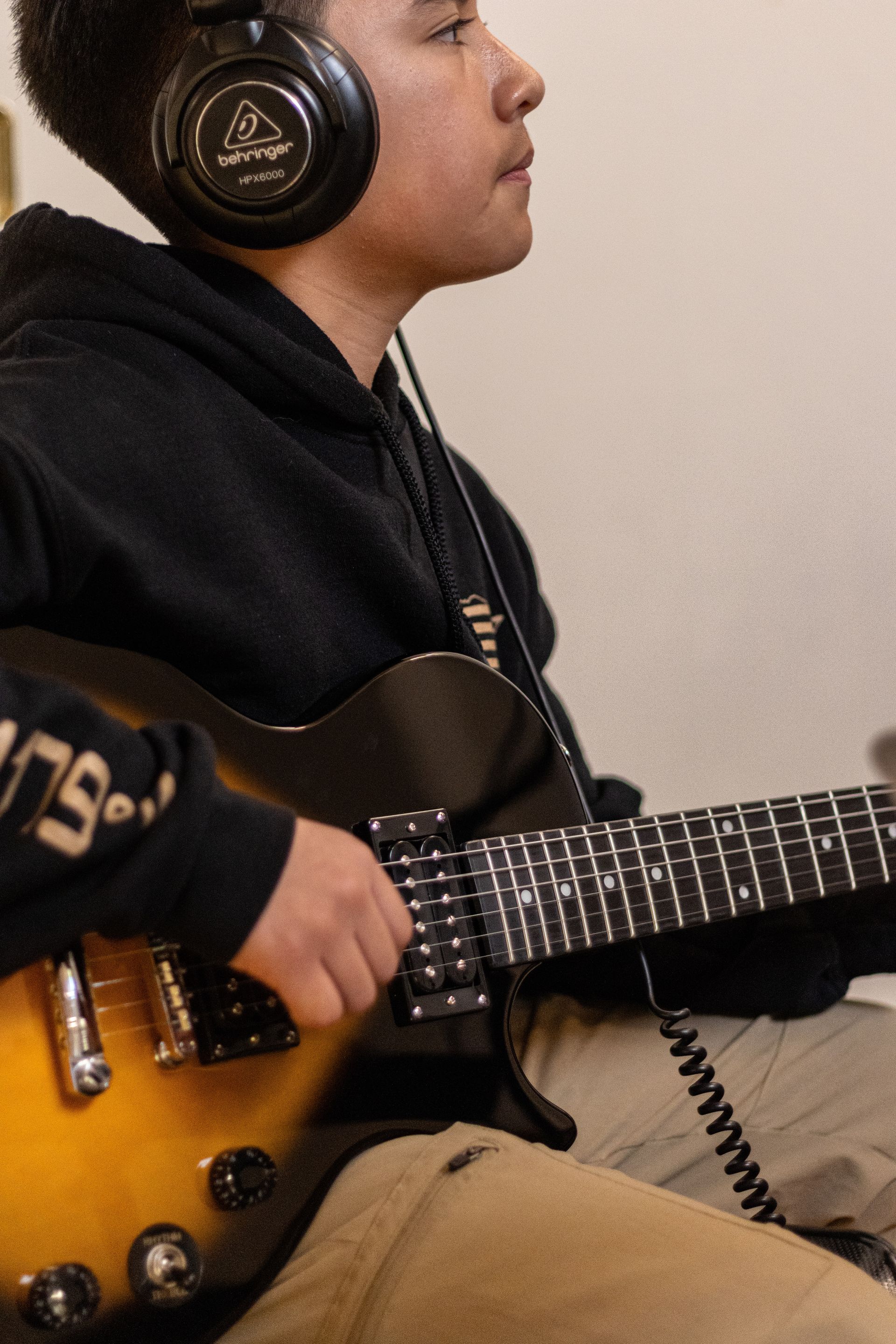 Person wearing headphones playing an electric guitar, indoors.