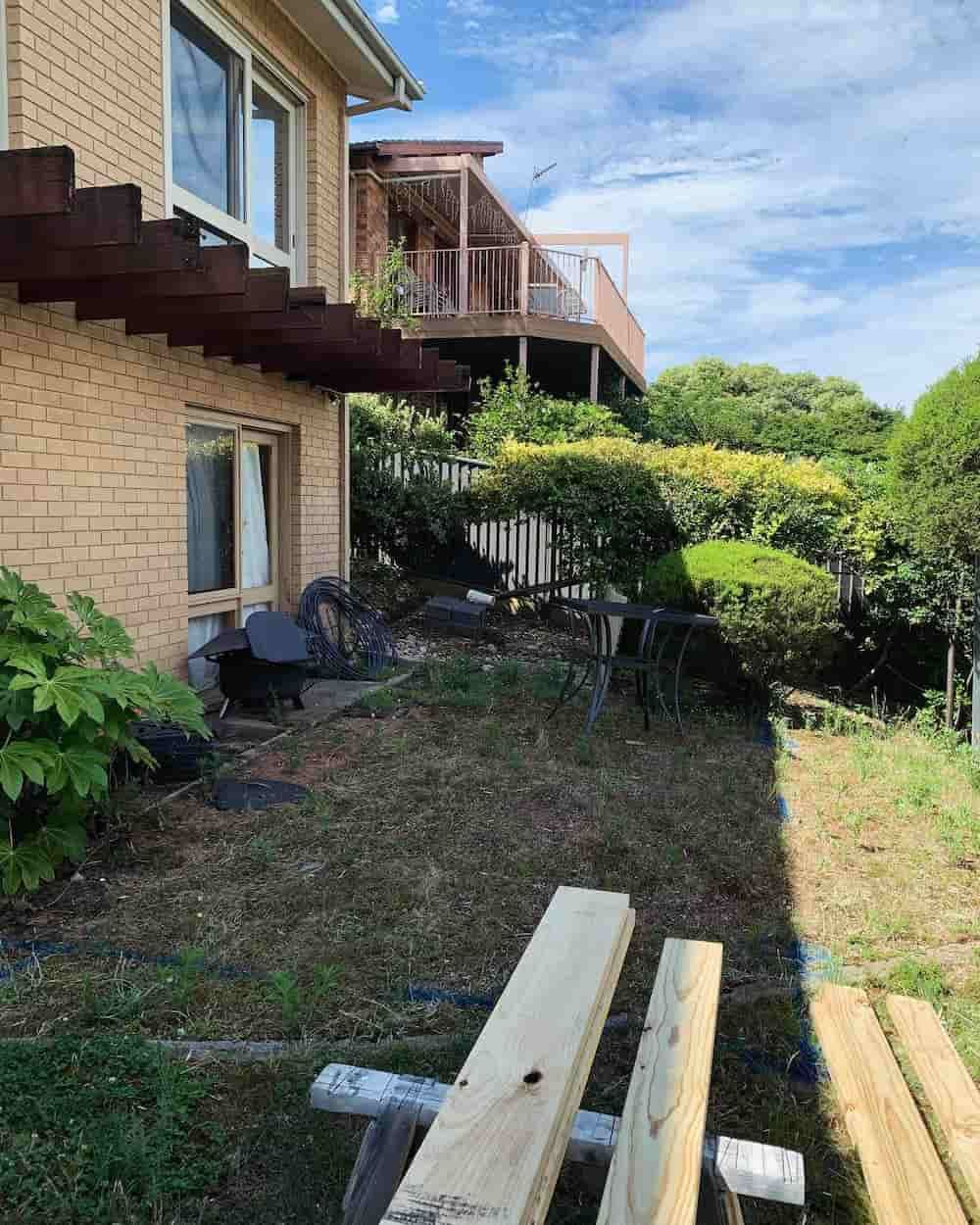 A Wooden Bench Is Sitting In Front Of A Brick House — Renovo Contractors In Monash, ACT