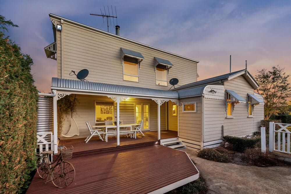 The Back Of A House With A Porch And A Table And Chairs On It — Renovo Contractors In Monash, ACT