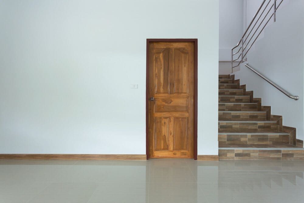 An empty room with a wooden door and stairs. — Renovo Contractors In Monash, ACT