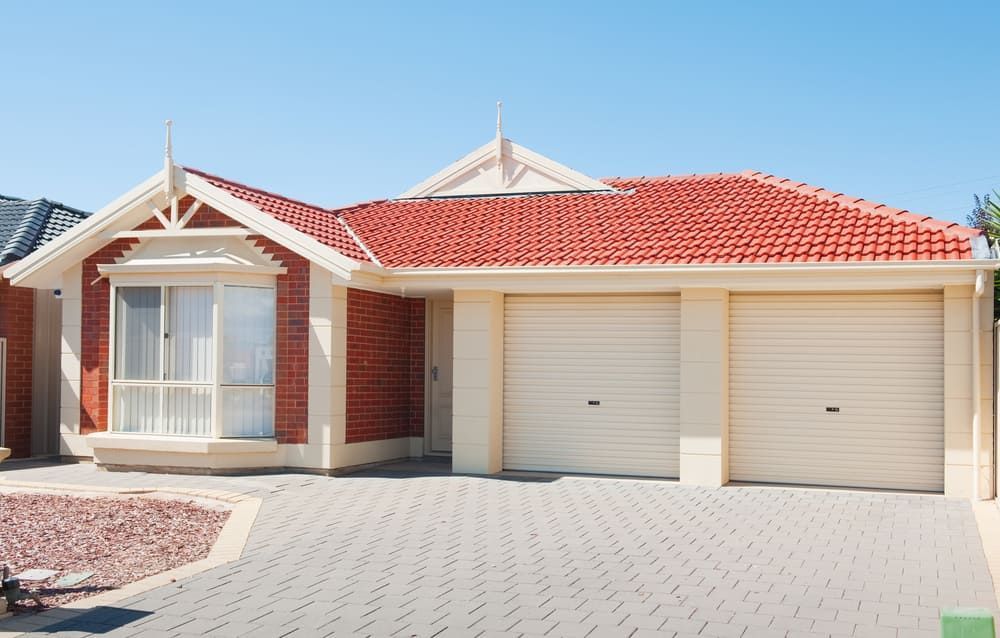 A House With A Red Roof And White Garage Doors — Renovo Contractors In Monash, ACT