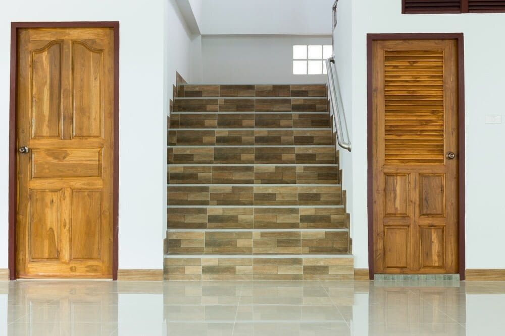 A Hallway With Three Wooden Doors And Stairs — Renovo Contractors In Monash, ACT
