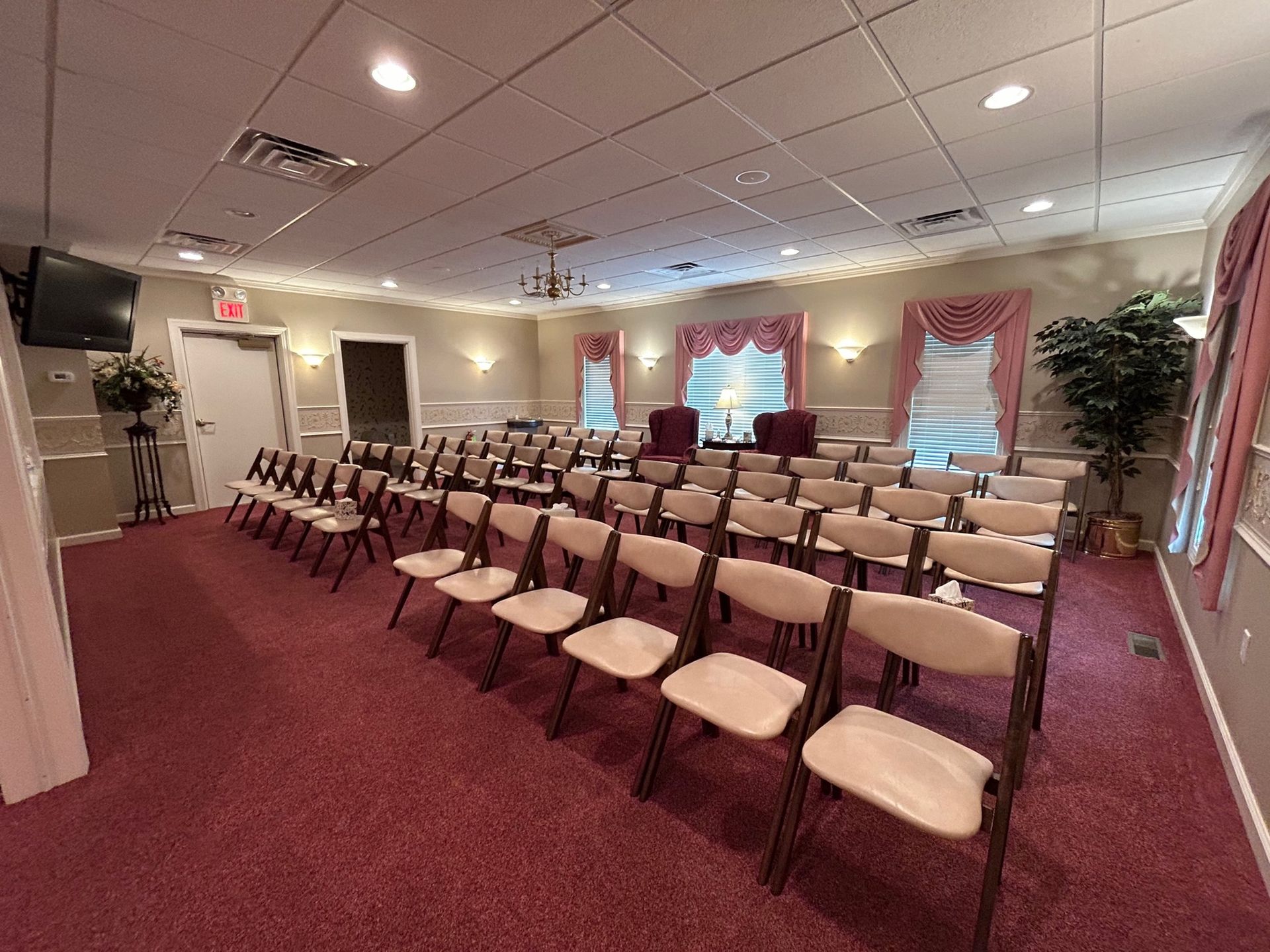 A chapel with rows of chairs facing a podium on a red carpet.