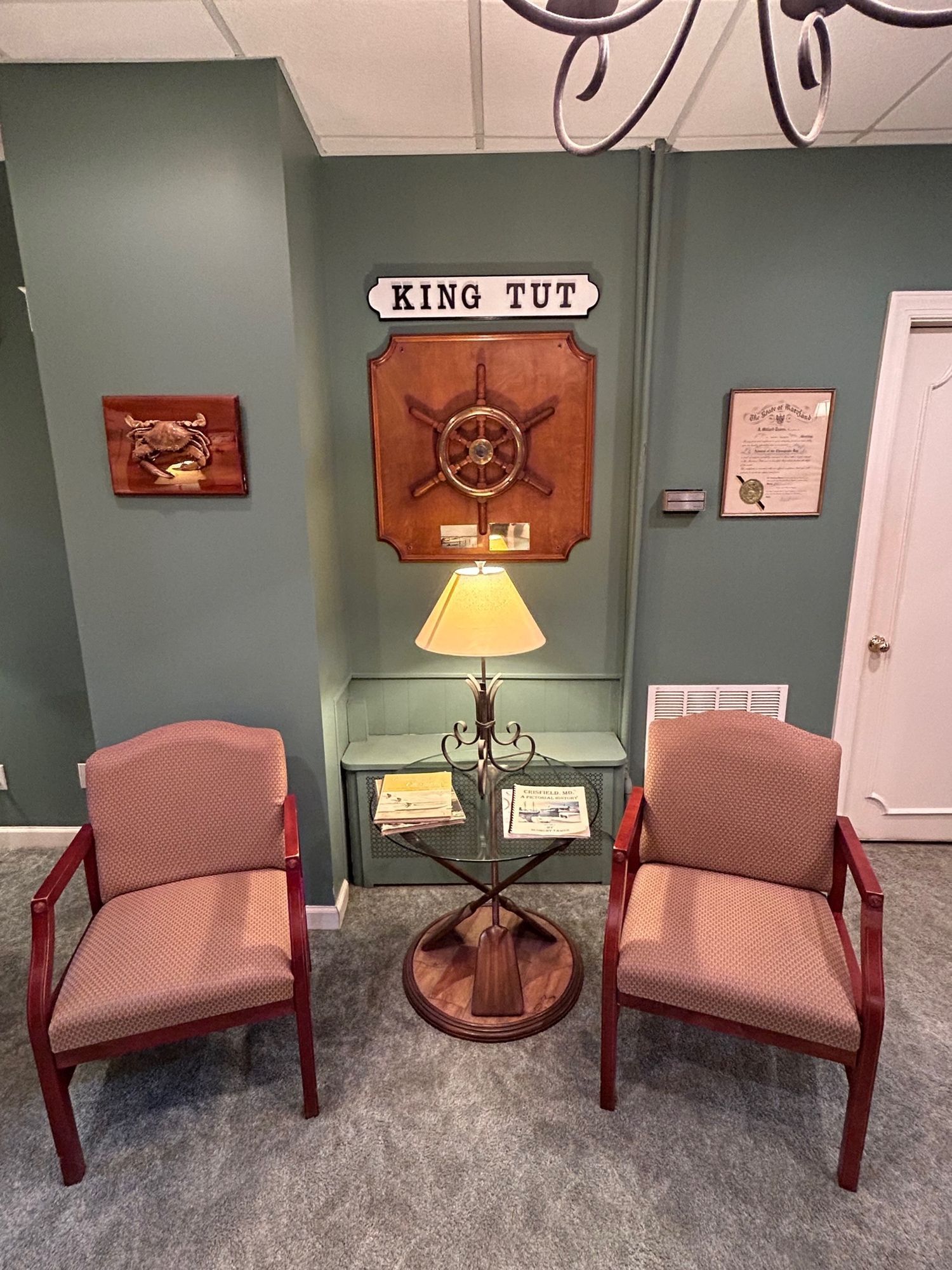 Two chairs face a King Tut display in a room with green walls and a lamp.