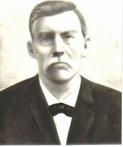 Man in suit and bow tie; stern expression. Black and white, formal portrait.