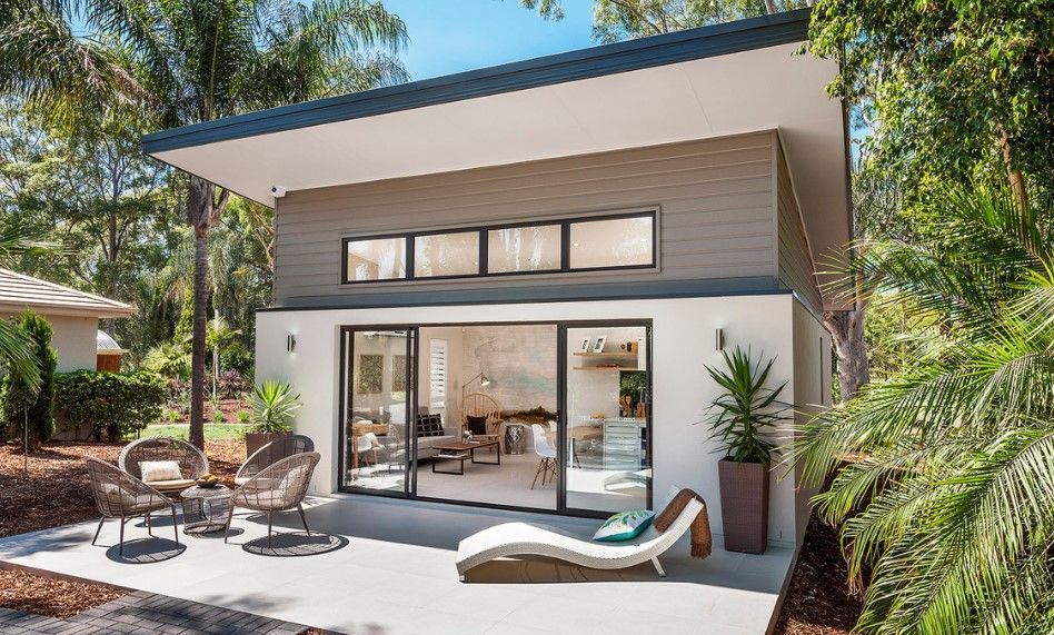 A small house with a patio and chairs in front of it.