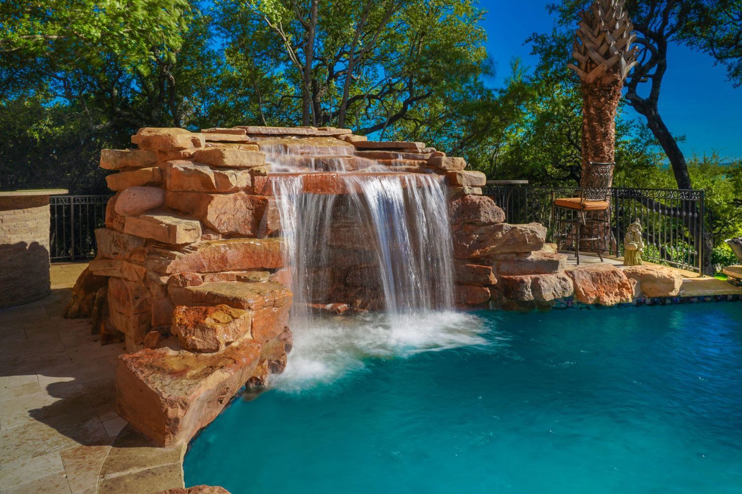 There is a waterfall in the middle of a swimming pool.