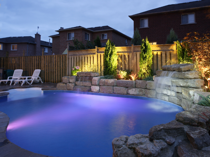 A swimming pool with purple lights and a waterfall