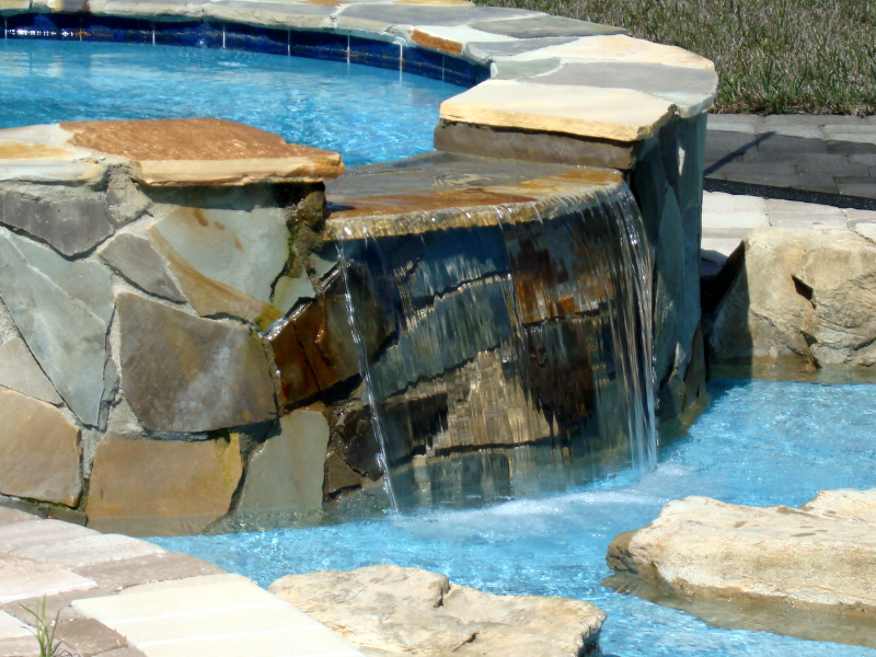 A waterfall is in the middle of a swimming pool