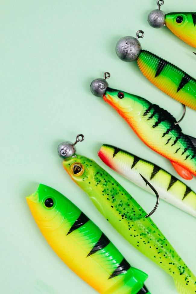 A group of green and yellow fishing lures with hooks on a green background.