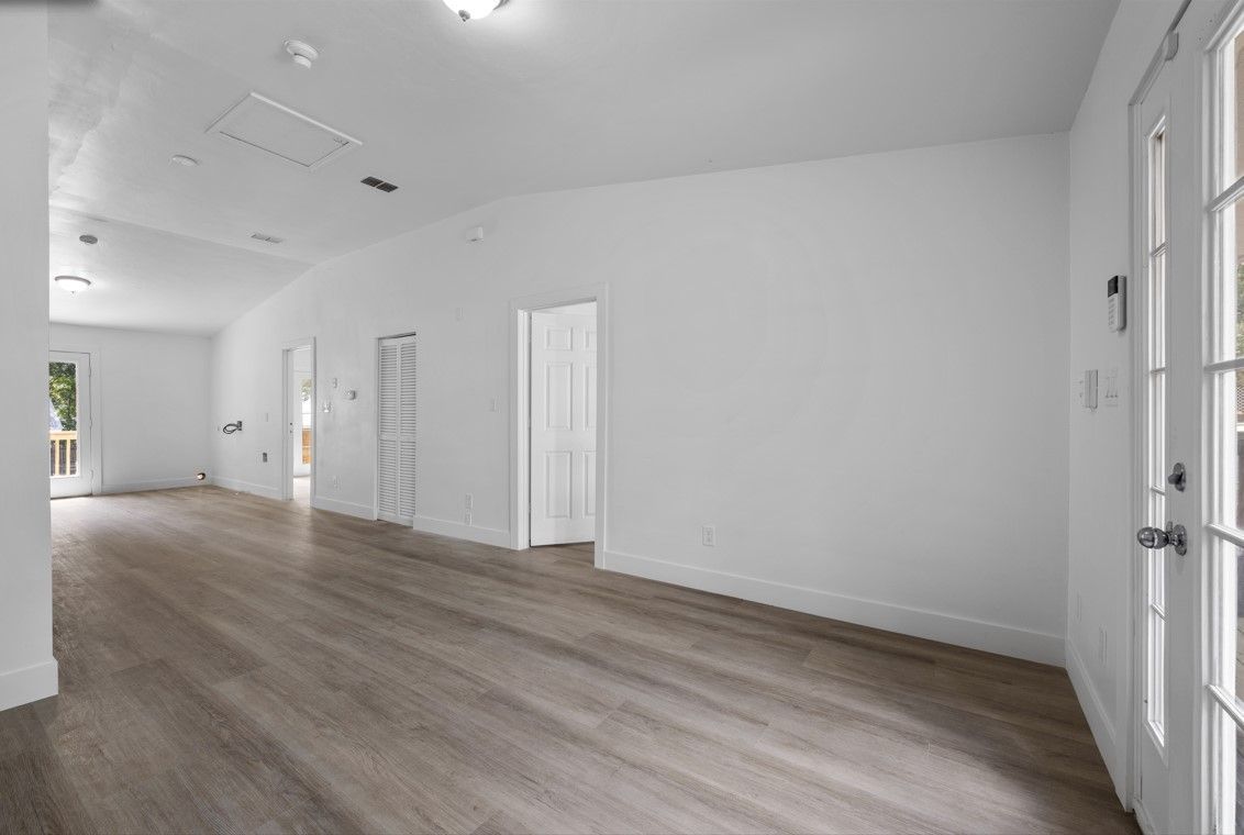 A large empty room with hardwood floors and white walls.