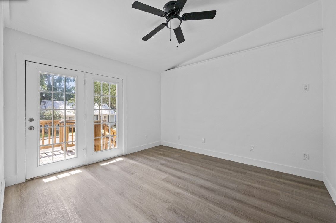 An empty living room with hardwood floors and a ceiling fan.
