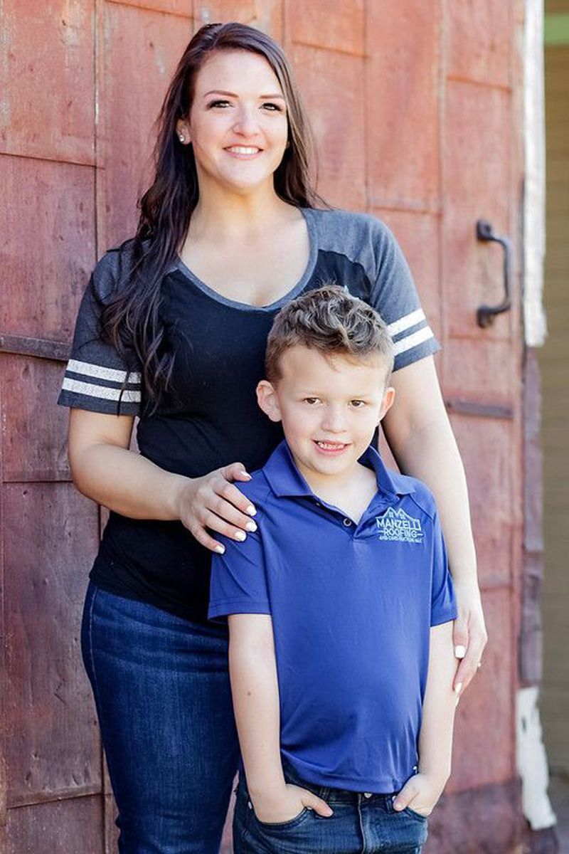 A woman and a boy are posing for a picture in front of a red wall.