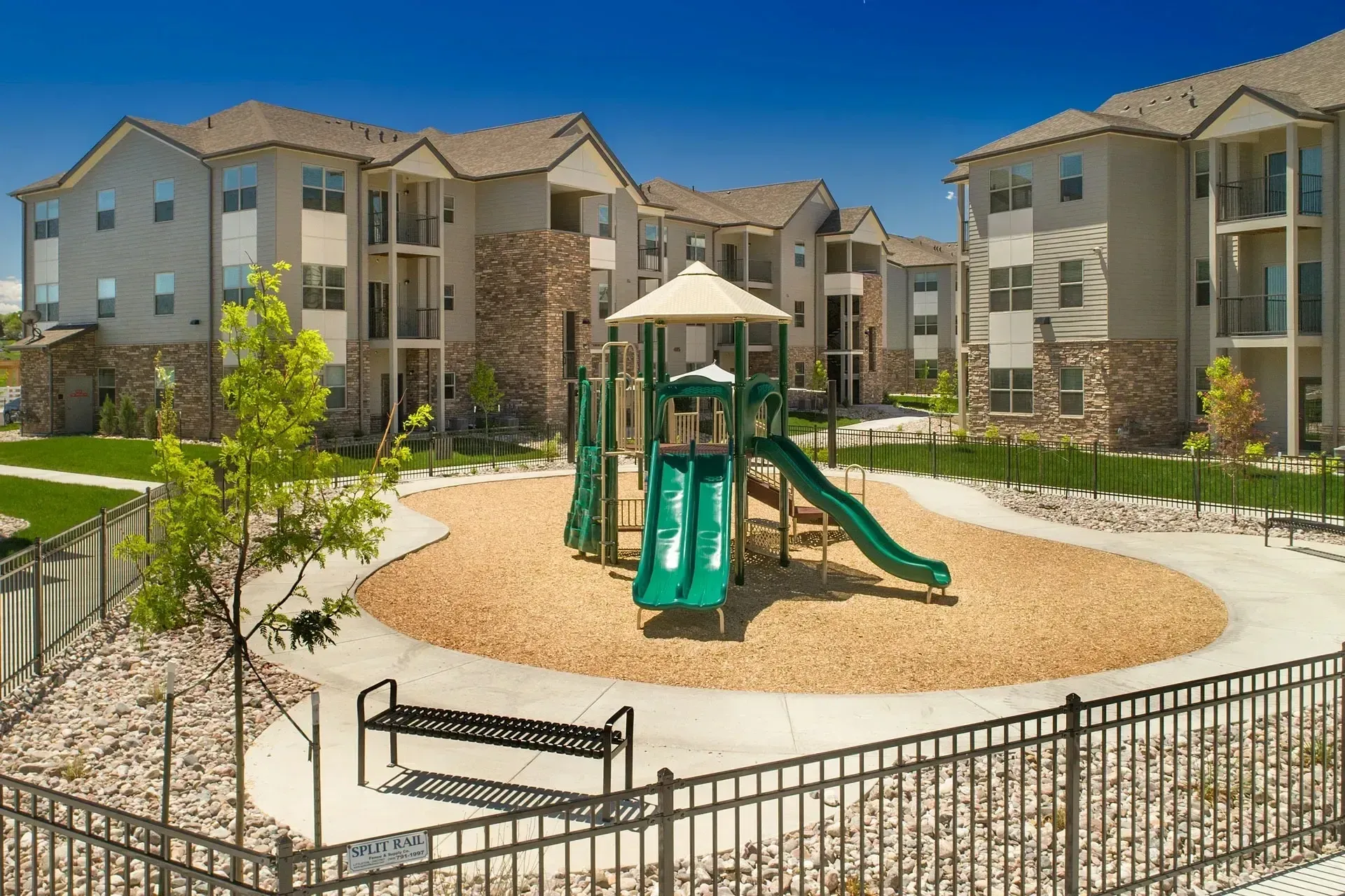 Apartment building courtyard with a playground, slide, and benches.